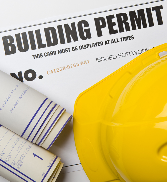 A construction helmet, building permit, and blue prints