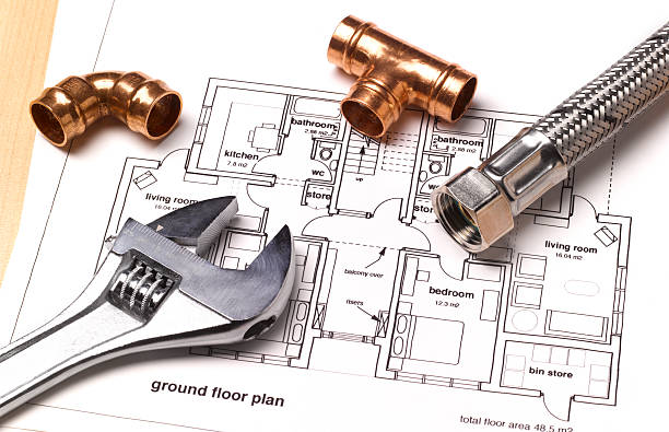 pipe wrench and pipe fittings placed on top of construction ground floor plan