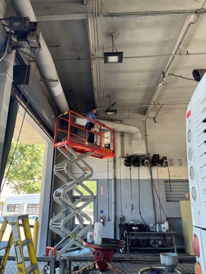 Building Maintenance Employee on a Ladder Working on Ducts